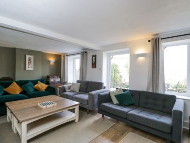 A living room with three sofas and a wooden coffee table at The Old School House in Lower Swell near Stow-On-The-Wold