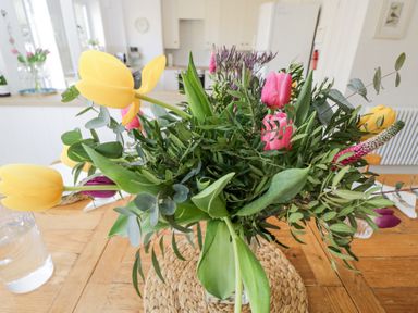 A bouquet of yellow and pink tulips with green foliage on a wooden table in a kitchen at The Old School House Lower Swell near Stow-On-The-Wold