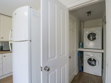 A utility room with a washing machine dryer and an iron near a kitchen fridge at The Old School House in Lower Swell near Stow-On-The-Wold