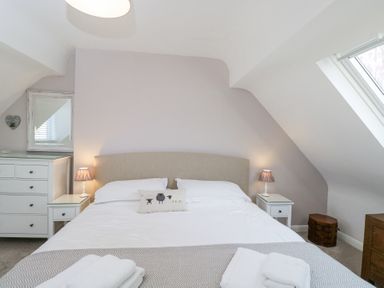 A bedroom with a bed two bedside tables lamps and a chest of drawers at The Old School House in Lower Swell near Stow-On-The-Wold