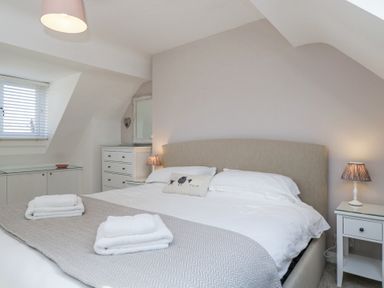 A bedroom with a bed side table lamps and folded towels on the bed at The Old School House in Lower Swell near Stow-On-The-Wold
