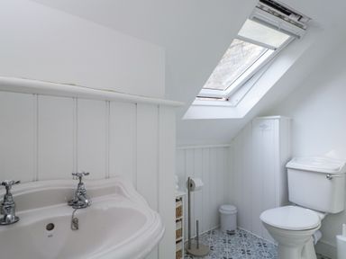 A bathroom with a sink toilet skylight and storage baskets at The Old School House in Lower Swell near Stow-On-The-Wold