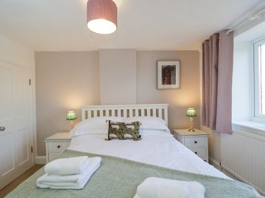 A bedroom with a bed bedside tables lamps and folded towels on the bed at The Old School House in Lower Swell near Stow-On-The-Wold
