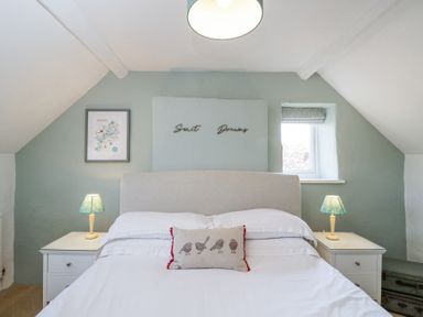 A bedroom with a bed a pillow with birds lamps on bedside tables and a window at The Old School House in Lower Swell near Stow-On-The-Wold