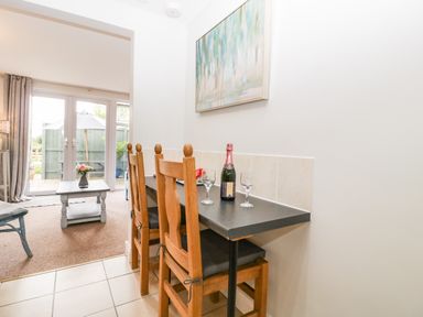 A dining area with wooden chairs a black countertop and a bottle with glasses at Thornhills Cottage in Othery near Middlezoy
