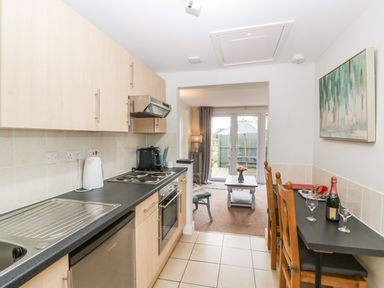 A kitchen with cabinets and appliances leading to a living area with a table and chairs at Thornhills Cottage in Othery near Middlezoy