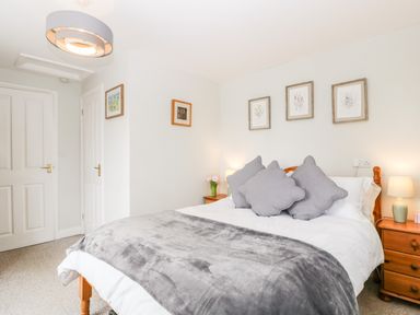 A bedroom with a bed gray pillows gray throw and wooden side tables with lamps at Thornhills Cottage in Othery near Middlezoy