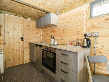 A kitchen with wooden walls countertop oven sink kettle and cabinets at Thornhills Lodge in Othery near Middlezoy