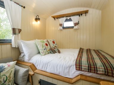 A small bedroom with a bed pillows and a blanket next to a window at Thornhills Lodge in Othery near Middlezoy