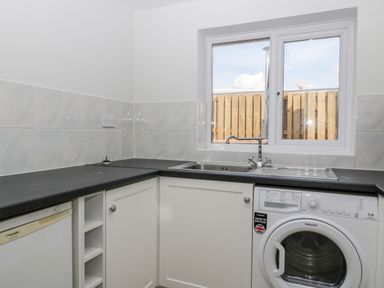 A utility room with a sink washing machine and fridge under a window at Somerset House in Othery near Middlezoy