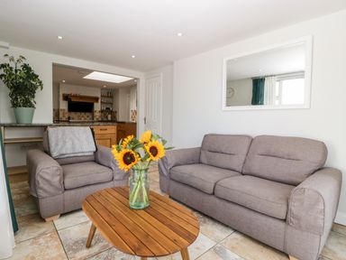 A living room with two gray sofas a wooden coffee table with sunflowers and a plant on a counter at Somerset House in Othery near Middlezoy