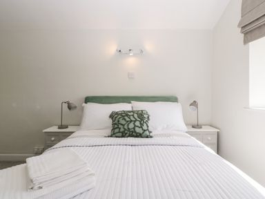 A bedroom with a bed with white linens and a green cushion between two bedside tables with lamps at Somerset House in Othery near Middlezoy