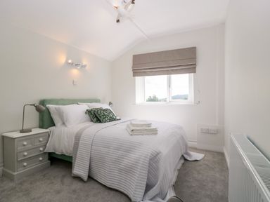 A bedroom with a bed bedside table window and radiator at Somerset House in Othery near Middlezoy