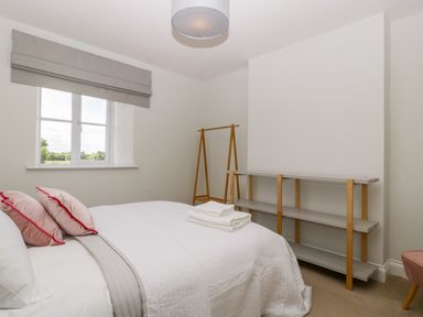 A bedroom with a bed folded towels window and shelves at Somerset House in Othery near Middlezoy