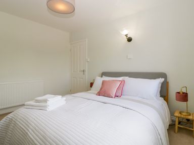 A bedroom with a bed with white bedding and a pink pillow at Somerset House in Othery near Middlezoy