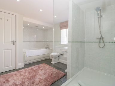 A bathroom with a bathtub toilet sink shower and pink rug at Somerset House in Othery near Middlezoy