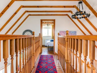 A hallway with wooden railings and beams leading to a bedroom at Baywatch Sands in Polzeath
