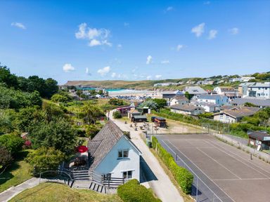 A coastal village with houses tennis courts greenery and a view of the beach at Baywatch Sands in Polzeath