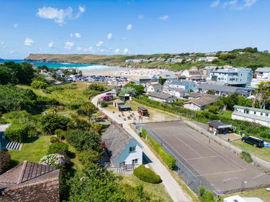 View of a beach town with houses a parking lot a tennis court and a sandy beach at Baywatch Sands in Polzeath