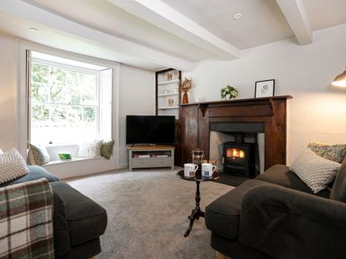 A sitting room with sofas a small table a fireplace and a television at Thorney How in Grasmere