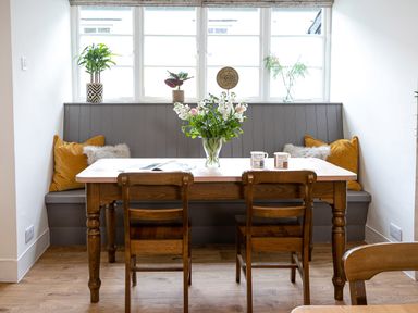 A dining area with a wooden table and chairs and a built-in bench with cushions at Thorney How in Grasmere