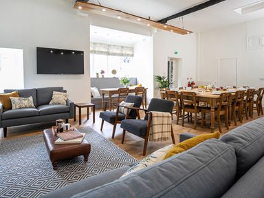 A sitting area with sofas chairs and a television next to a dining table with chairs at Thorney How in Grasmere