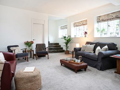 A living room with a sofa armchairs coffee table and plants at Thorney How in Grasmere