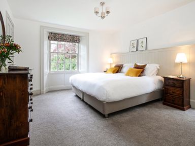 A bedroom with a bed nightstands a window and a dresser with flowers at Thorney How Grasmere