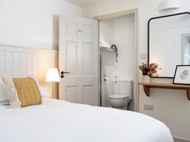 A bedroom with a bed a lamp and an open door showing a bathroom at Thorney How in Grasmere
