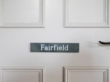 A white door with decorative panels a black handle and a sign reading Fairfield at Thorney How in Grasmere