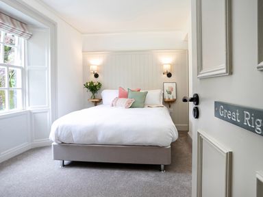 A bedroom with a double bed with pillows wall lights and a window at Thorney How in Grasmere