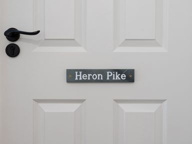 A white door with a black handle and a sign that reads Heron Pike