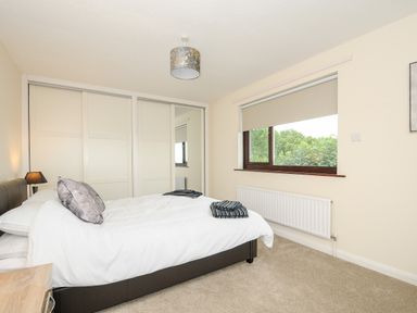 A bedroom with a double bed folded clothes bedside table window and wardrobe with sliding doors at Spring Lodge in Eastcott near Kilkhampton