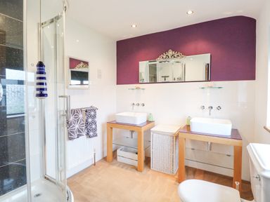 A bathroom with two sinks and mirrors a shower and a toilet at Willow Cottage in Hickling near Catfield