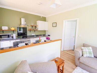 A kitchen and living area with a countertop set for two with wine glasses and a bottle at Cam O'r Fechan Annexe in Llangollen