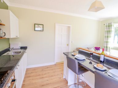 A kitchen area with countertop stools glass of wine and wine bottle at Cam O'r Fechan Annexe in Llangollen