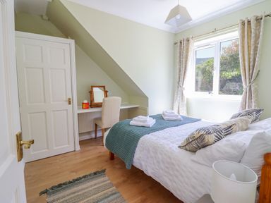 A bedroom with a bed folded towels a desk chair window and curtains at Cam O'r Fechan Annexe Llangollen
