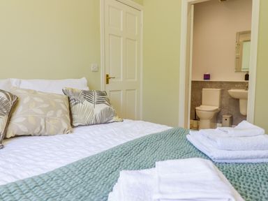 A bedroom with a bed and towels with an open bathroom door at Cam O'r Fechan Annexe in Llangollen