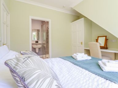 A bedroom with a bed with towels on it a wardrobe and a desk with a chair and mirror at Cam O'r Fechan Annexe in Llangollen