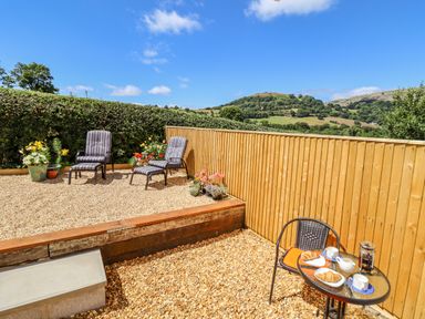 An outdoor patio with two chairs and a small table with croissants and coffee at Cam O'r Fechan Annexe in Llangollen