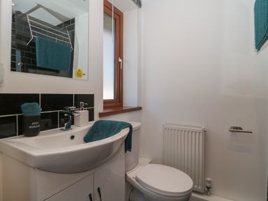 A bathroom with a sink a toilet a mirror and a window at Bluebell Lodge Meadow view lodges in Brean