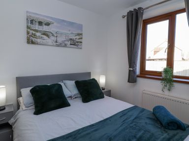 A bedroom with a bed two bedside tables lamps and a window at Bluebell Lodge Meadow view lodges in Brean