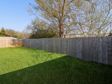 A fenced backyard with grass and trees at Bluebell Lodge Meadow view lodges Brean