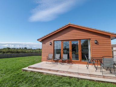 An outdoor area with a cabin and chairs at Delphine Lodge, Meadow View Lodges Brean