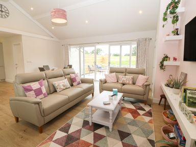 A living room with two sofas a coffee table and sliding glass doors at Y Beudy in Dinas near Bontnewydd