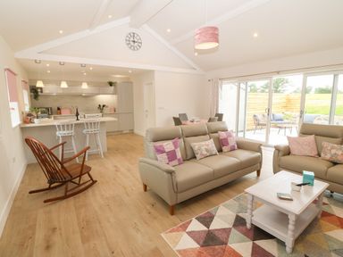 An open living room and kitchen with sofas and rocking chair at Y Beudy in Dinas near Bontnewydd