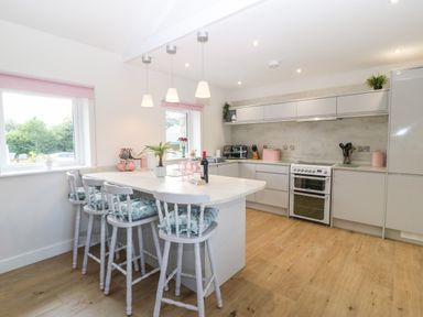 A kitchen with a breakfast bar and four chairs with cushions at Y Beudy in Dinas near Bontnewydd
