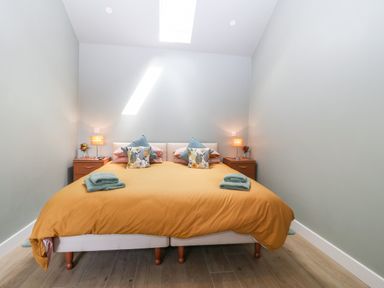 A bedroom with a double bed yellow duvet side tables with lamps and flowers at Y Beudy Dinas near Bontnewydd