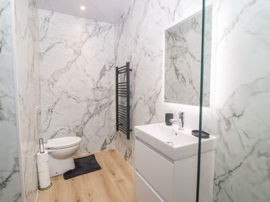 A bathroom with a toilet sink mirror black towel rack and toilet paper at Y Beudy in Dinas near Bontnewydd