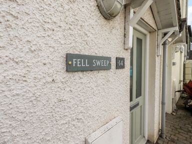 A house entrance with a green door and a sign reading Fell Sweep number 14 in Keswick